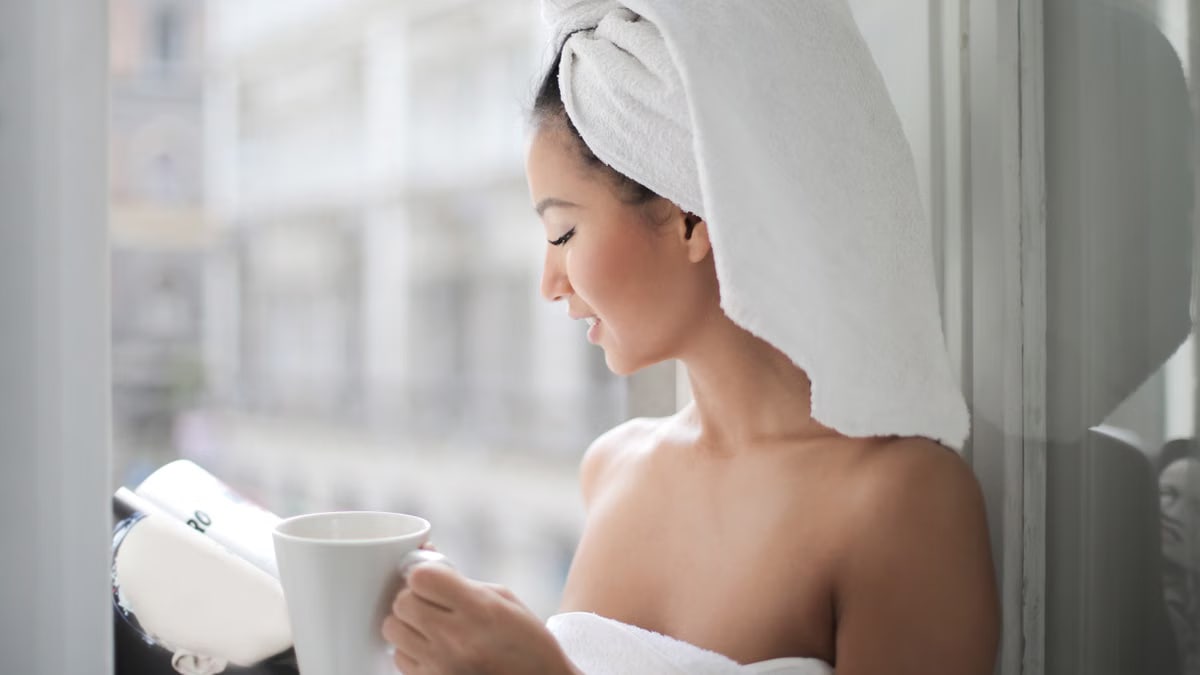 A woman enjoying a quiet moment with coffee and a book in natural light by a window.